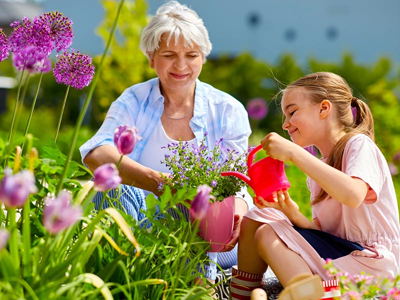 a lady and a girl watering plants in a yard with Group Health Insurance in Medina, OH, Fairlawn, Strongsville, Valley City, OH, Hinckley, OH, Litchfield, OH